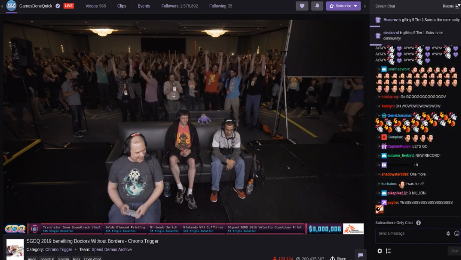 A screenshot of a gaming marathon shows a crowd of people watching behind gamers playing as well as a stream of online comments.