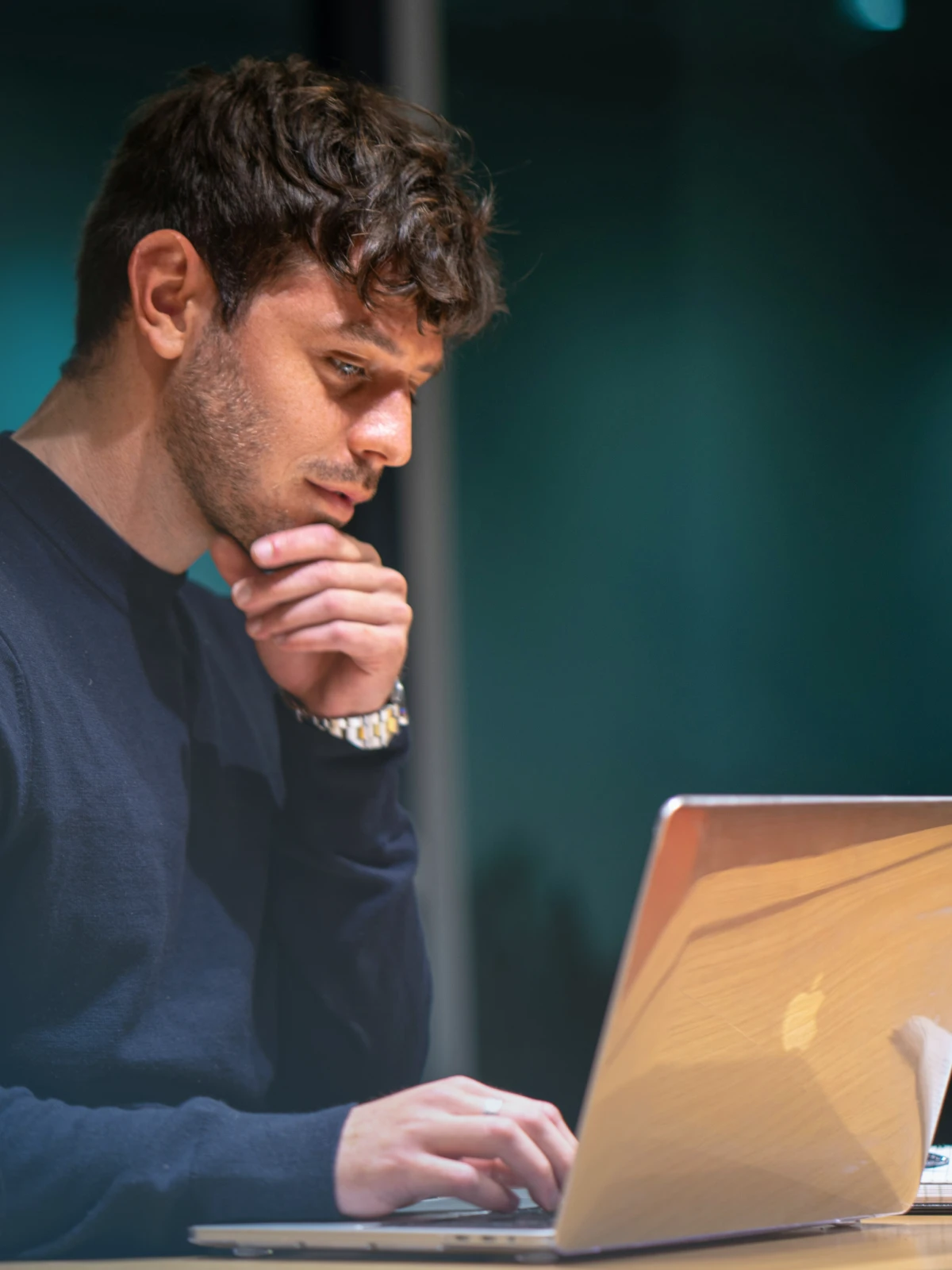 A man looking thoughtfully at a laptop screen.