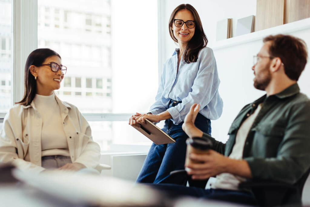 Three enterprise workers having a meeting about hosting plans in a corporate office.