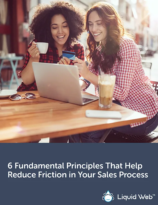 Two woman at a coffee shop looking at laptop with credit card in hand going through sales process