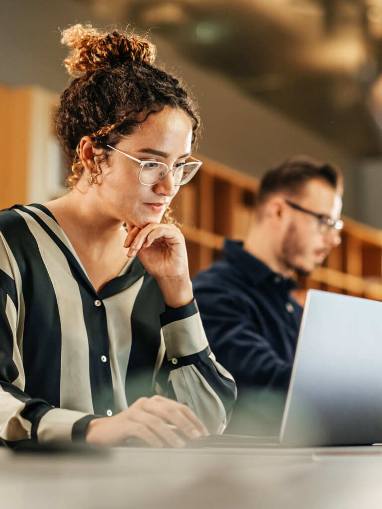A happy young woman working on computer in a modern bright office.