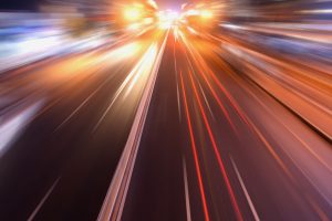 Picture of a car heading down a highway at blurred speeds.