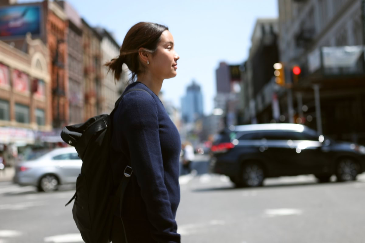 Photo of a woman crossing the street wearing a backpack