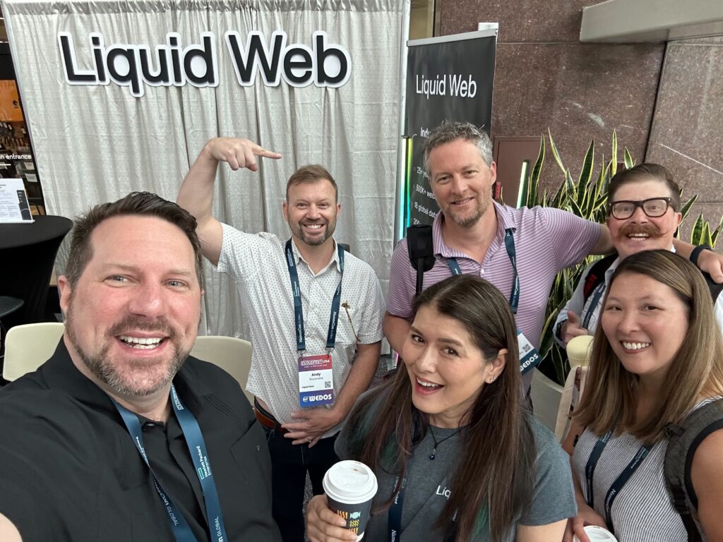A few members of the Liquid Web team pose for a photo with friends at their booth