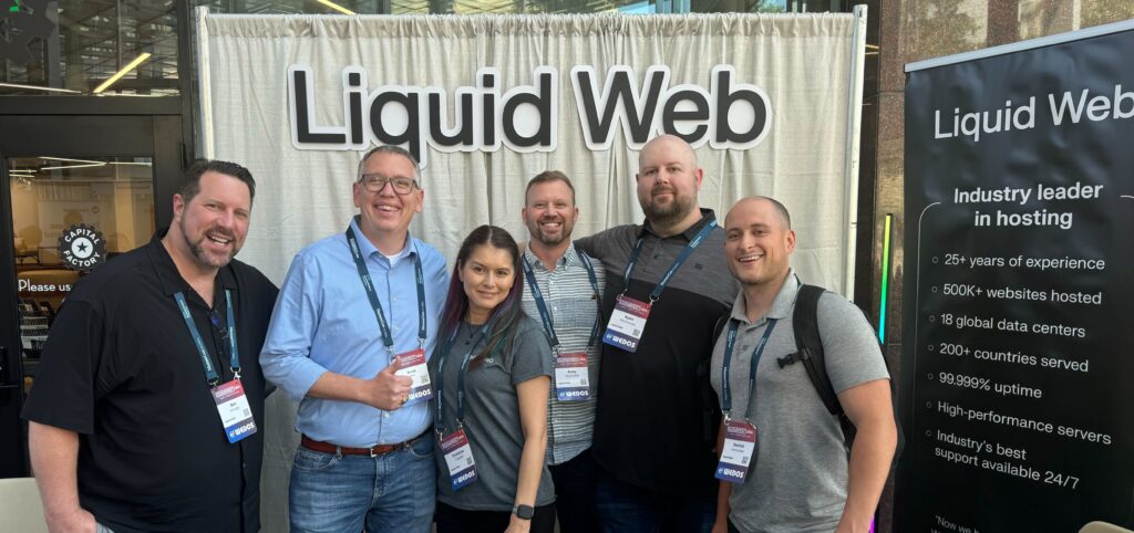 The Liquid Web field team posing for a picture in front of their booth