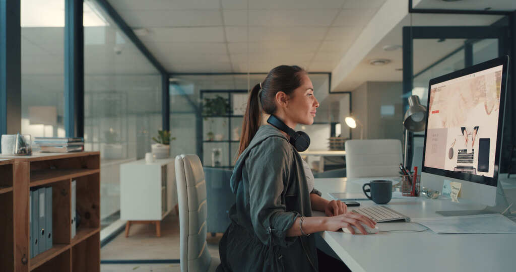 A woman sits at a desk in an office as she sets up her Magento hosting by choosing a data center