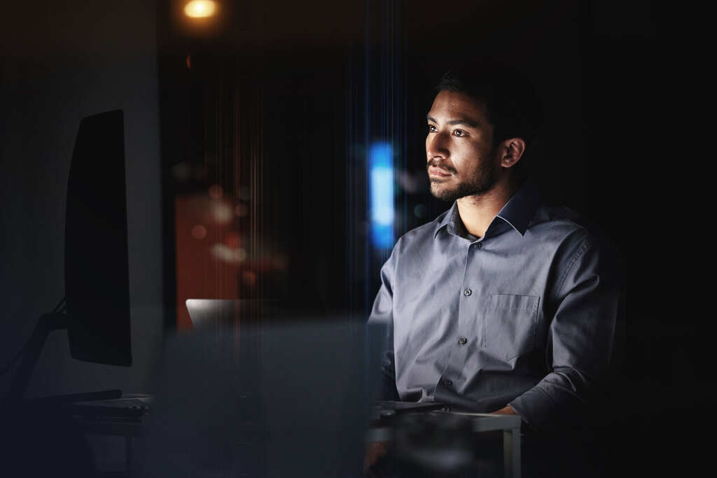 A man looks intently at a large computer monitor as he compares managed WooCommerce hosting plans