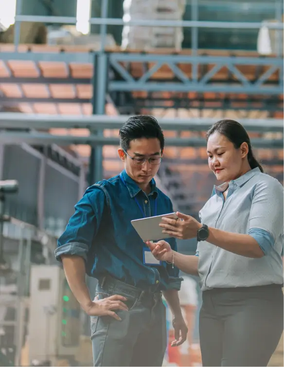 Two workers in a warehouse compare dedicated server options on a tablet