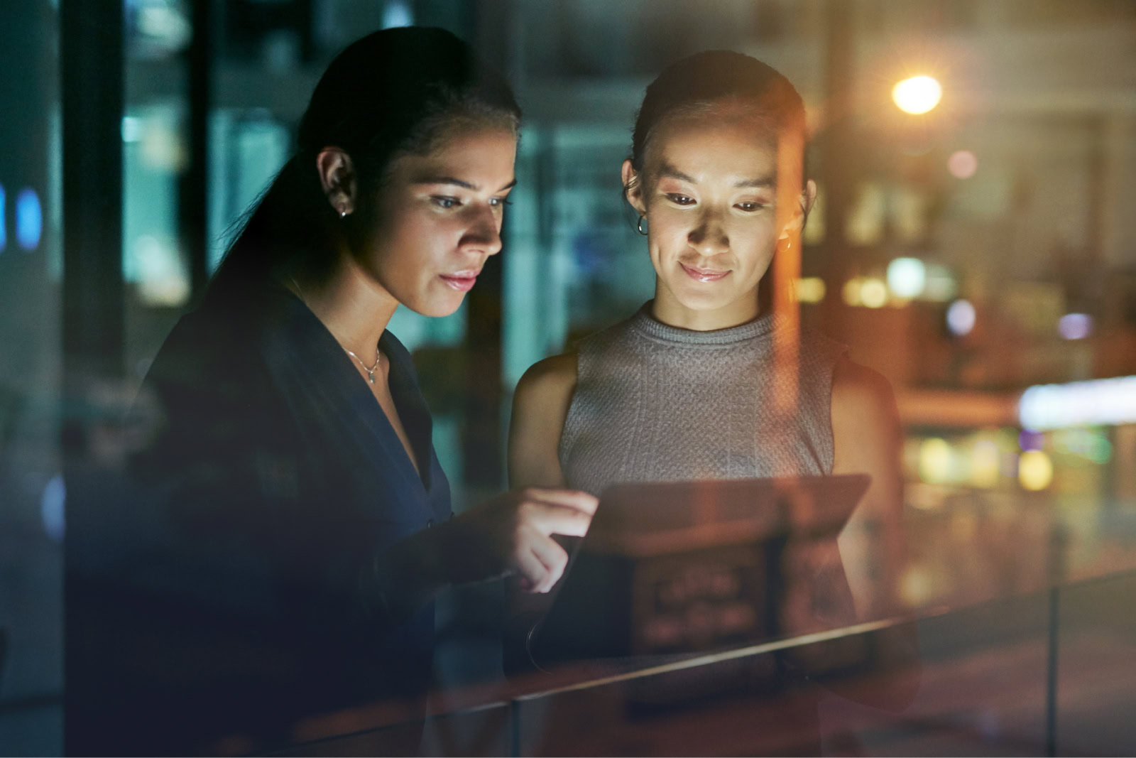 Two women looking at a tablet discussing the business advantages of bare metal servers for ecommerce.