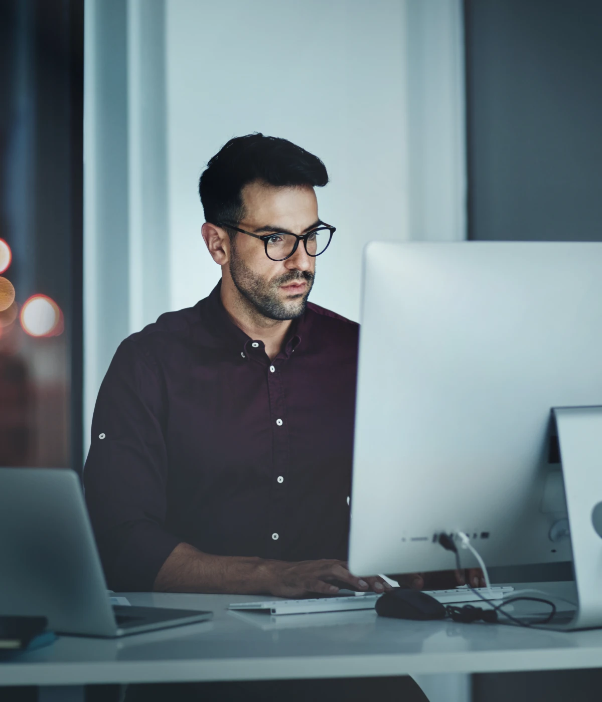 Man sits at a desk staring at a desktop computer