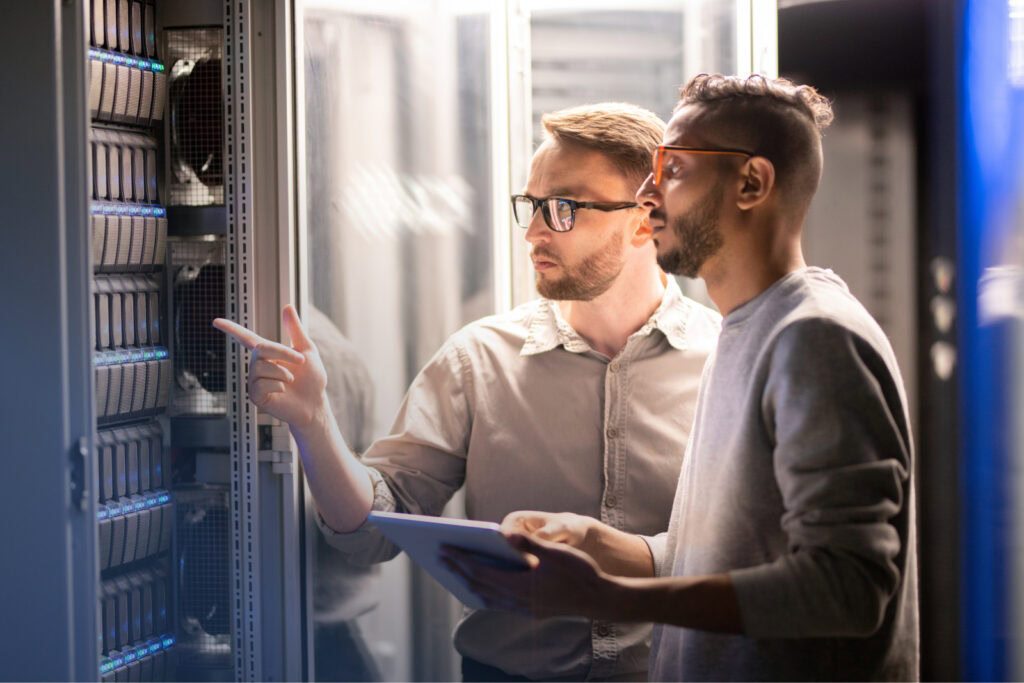 Two men stand with a tablet and examine a server
