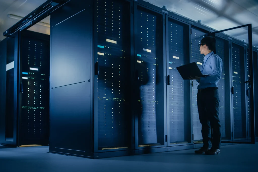 Man holding laptop in a data center.