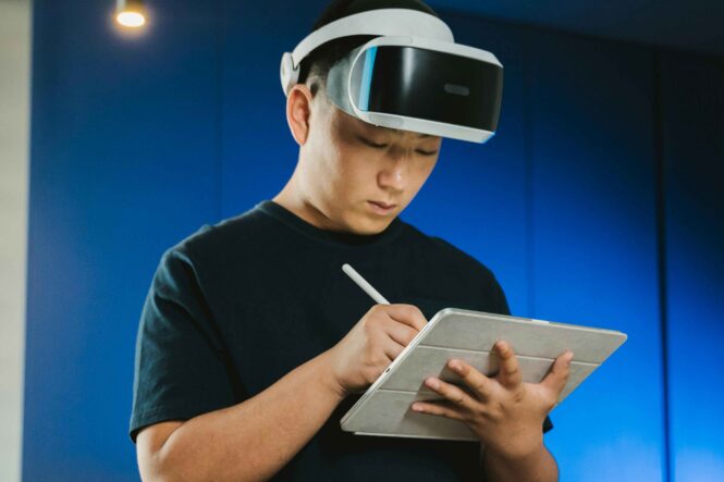 A man wearing a VR headset and writing on a tablet as an example of integrating AR/VR into live event activities