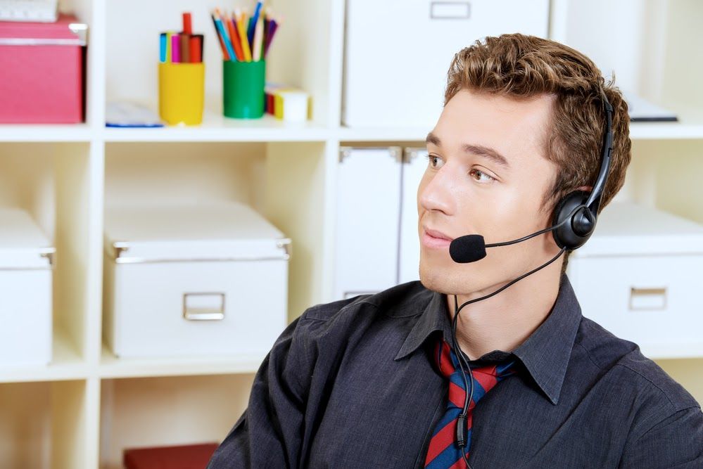 A man with a headset on, sitting in an office setting.