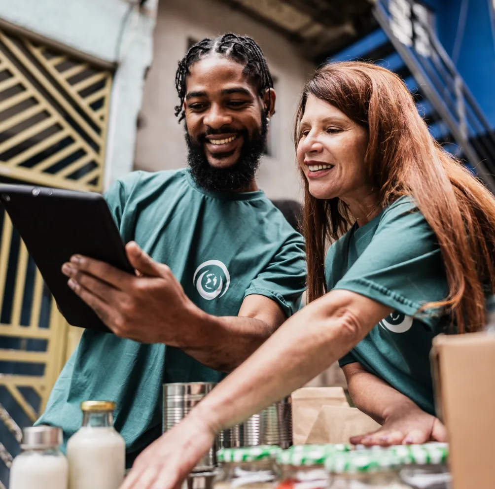 Man and woman in volunteer t-shirts looking at their fundraising campaign on an i-pad.