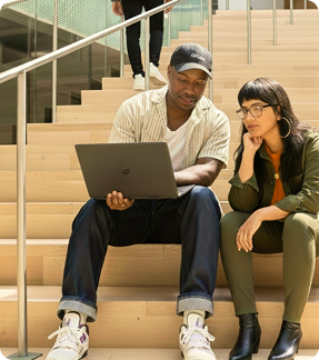 man and woman sitting on steps looking at a laptop collaborating