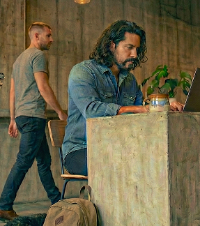 Male developer sitting at a concrete desk, with porcelain coffee mug next to his laptop