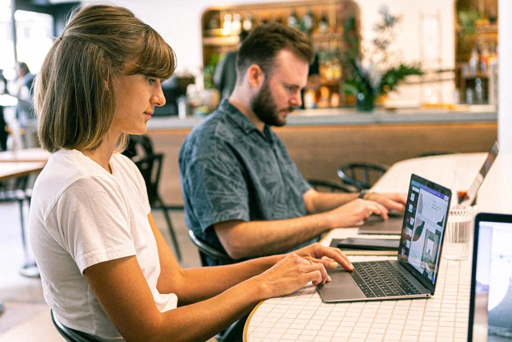 Photo Of Woman Using Laptop Next To Her Agency Coworker